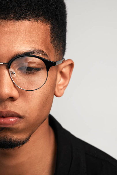 Living in deep thought. Cropped studio shot of a handsome young man wearing glasses and contemplating while standing against a grey background - Fotografie, Obrázek