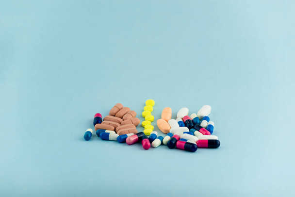 Ένας σωρός από πολύχρωμα χάπια. Φάρμακα, χάπια στοιβαγμένα σε μπλε φόντο. Ιατρικές προμήθειες. - Φωτογραφία, εικόνα