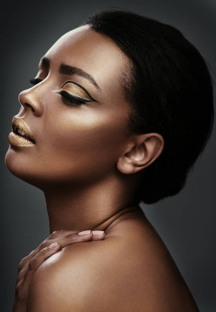 Magnify the beauty that already exists. a beautiful young woman wearing gold makeup against a grey background - Fotó, kép