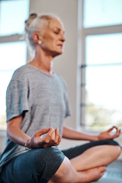 No distractions at all. a cheerful mature woman practicing yoga while meditating inside of a studio during the day - Foto, Imagem