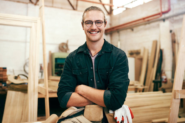Мбаппе является экспертом в этой области. Портрет красивого молодого плотника, позирующего со сложенными в мастерской руками - Фото, изображение