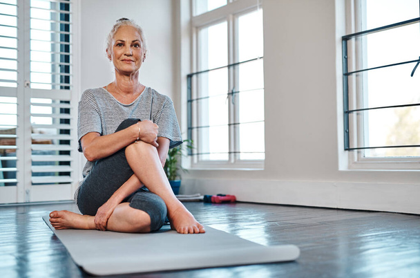 Time to get my yoga on. Portrait of a cheerful mature woman practicing yoga inside of a studio during the day - Fotoğraf, Görsel