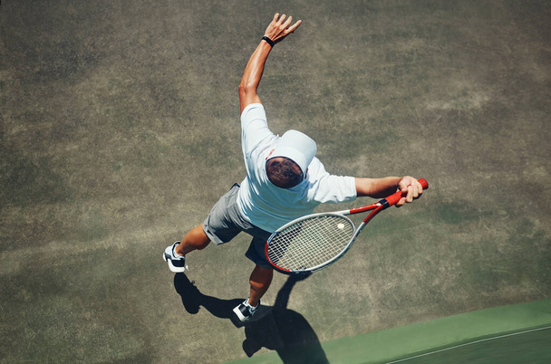 Я виграю сет. Високий кут стрільби зосередженого чоловіка середнього віку, який грає в теніс на вулиці на тенісному корті вдень
 - Фото, зображення