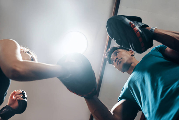 Now heres the tricky part... Low angle shot of a handsome young male fitness instructor coaching a female boxer in a gym - Foto, Imagem
