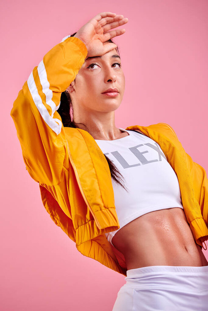 All your efforts will leave you glowing. Studio shot of a sporty young woman wiping her forehead against a pink background - Fotografie, Obrázek
