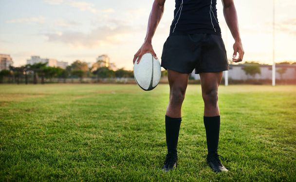 Nothing can stop me. an unrecognizable sportsman standing alone and holding a rugby ball during a morning practice - Foto, Imagen