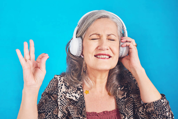 Ця пісня повертає мене до старих старих часів. фанк і весела старша жінка, слухаючи музику на своїх навушниках на синьому фоні
 - Фото, зображення