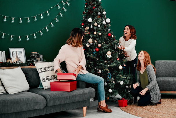 The tree is looking great. three attractive middle aged women decorating a Christmas tree together at home - Fotoğraf, Görsel