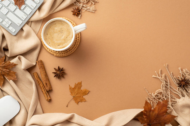 Autumn business concept. Top view photo of cup of frothy cocoa on rattan serving mat computer mouse keyboard yellow maple leaves cinnamon sticks anise and plaid on isolated beige background - Foto, Bild