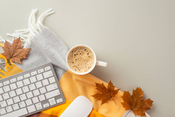 Autumn business concept. Top view photo of workplace yellow maple leaves keyboard computer mouse cup of hot drinking and plaid scarf on isolated grey background - 写真・画像