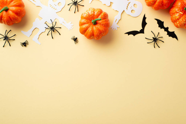 Halloween party concept. Top view photo of pumpkins spiders skeleton and bats silhouettes on isolated beige background with copyspace - Photo, Image