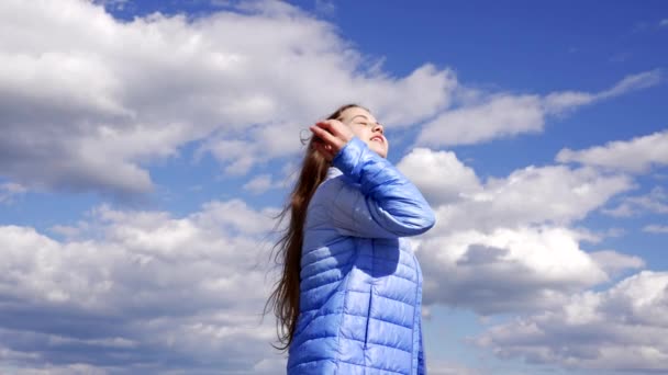 счастливый ребенок в осенней куртке наслаждаться солнцем с красивыми волосами на фоне неба, длинные волосы. - Кадры, видео