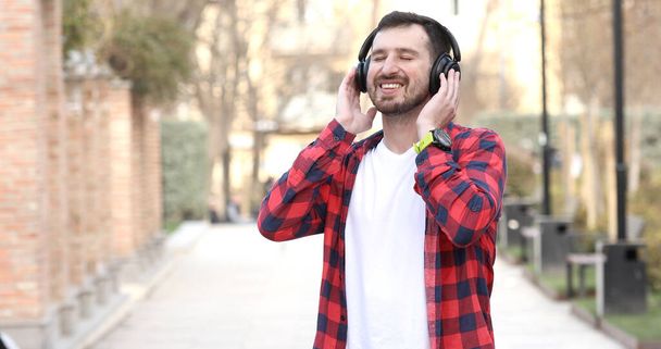 Modern young smiling man enjoying music outdoor. - Photo, Image