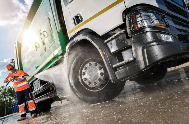 Heavy Equipment Washing Station Worker in His 40s Pressure Wash a Garbage Truck - 写真・画像
