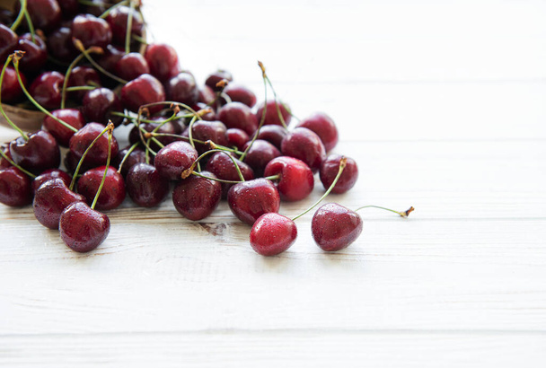 Fresh red cherries fruit on a white wooden background - Zdjęcie, obraz