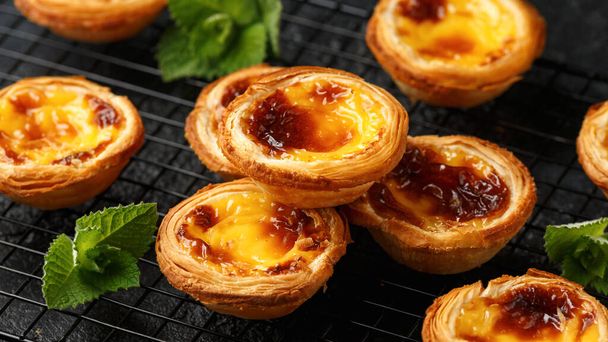 Traditional Portuguese custard tarts or Pastel de Nata freshly baked and cooling on rack. - Photo, Image