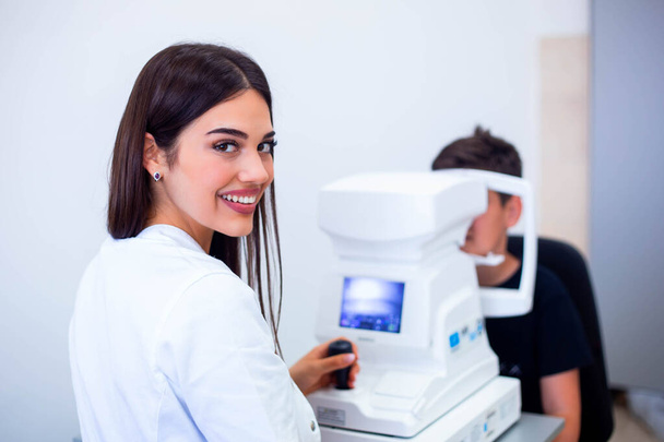 Naispuolinen silmälääkäri käyttää konetta silmänäön tarkistamiseen klinikalla. Pieni poika katselee laitteita ja lääkäri testaus silmä oppilas optisessa kaupassa. Silmien hoidon ja terveyden käsite
 - Valokuva, kuva