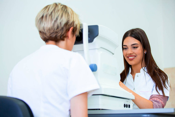 Medico oftalmologo femminile sta controllando la visione degli occhi di attraente giovane donna in clinica moderna. Medico e paziente in clinica oftalmologica
 - Foto, immagini