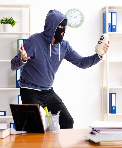 O ladrão em Balaclava no escritório
 - Foto, Imagem