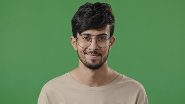 Portrait arabic young guy in studio on green background feel energetic close-up smiling bearded man with glasses looking at camera happy client satisfied with service in dental or ophthalmology clinic - Imágenes, Vídeo