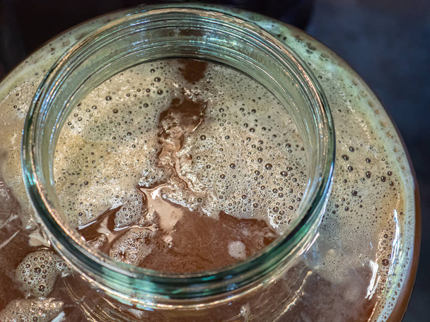 Close-up of craft beer and foam in a fermentation container. Process of making home beer from malt. Craft beer from barley and dark malt. - 写真・画像