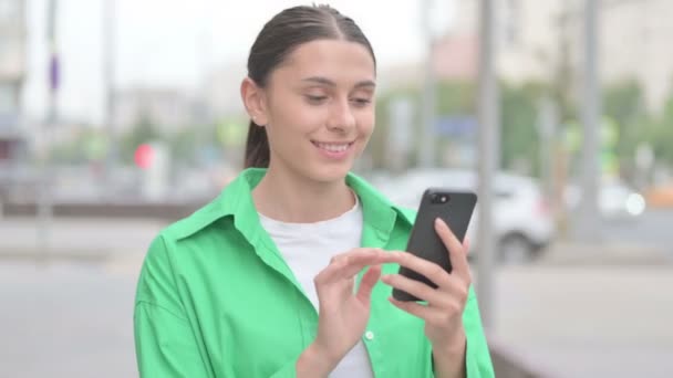 Νεαρή γυναίκα γιορτάζει σε απευθείας σύνδεση επιτυχία στο Smartphone Εξωτερική - Πλάνα, βίντεο
