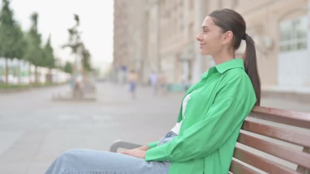 Νεαρή γυναίκα χαμογελά στην κάμερα, ενώ κάθεται στον πάγκο - Πλάνα, βίντεο