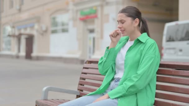 Молода жінка кашляє, сидячи на вулиці - Кадри, відео