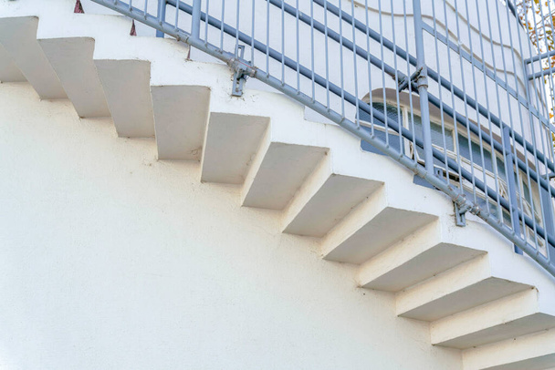 Вид с низкого угла на изогнутую лестницу с железными перилами в Сан-Франциско, Калифорния. Внешний вид здания с белыми стенами и круглой лестницей снаружи. - Фото, изображение