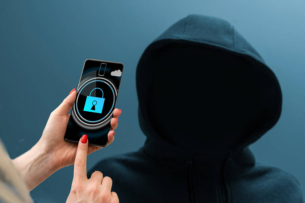 άνθρωπος σε μια κουκούλα Hacker, smartphone με κλειδαριά. - Φωτογραφία, εικόνα