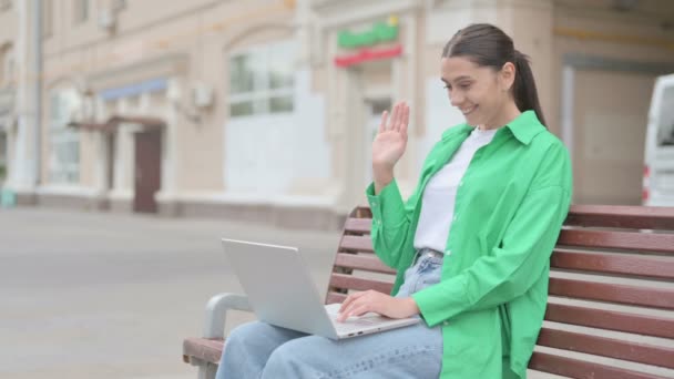 Νεαρή γυναίκα μιλάει σε βίντεο κλήση, ενώ κάθεται σε υπαίθριο χώρο στο Bench - Πλάνα, βίντεο