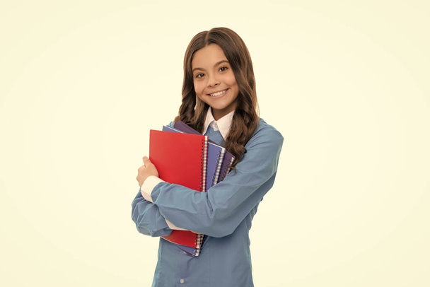 vrolijk gezicht van tiener meisje met lang krullend haar hold school werkboek geïsoleerd op wit, huiswerk. - Foto, afbeelding