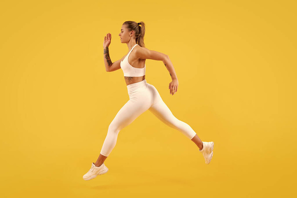 спортивна жінка біжить на жовтому фоні
. - Фото, зображення