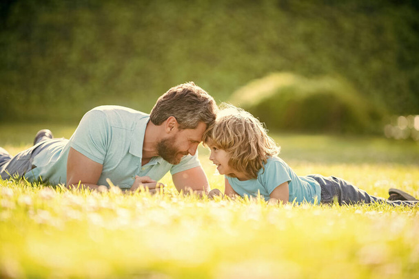 lovely dad with kid on summer day. parenting and fatherhood. fathers day. loving father and son having fun in park. family value. childhood and parenthood. parent relax with little child boy on grass. - Photo, Image