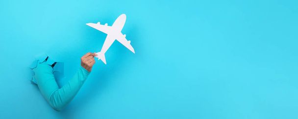 white airplane in hand over blue background, panoramic layout - 写真・画像