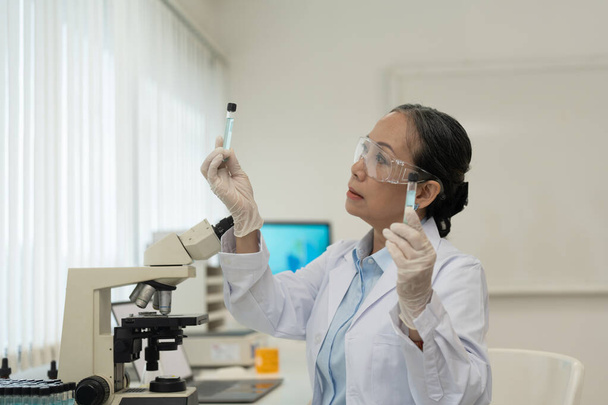 Portrait of Senior Scientist Looking Under Microscope Does Analysis of Test Sample. Ambitious Young Biotechnology Specialist, working with Advanced Equipment - Foto, Imagen