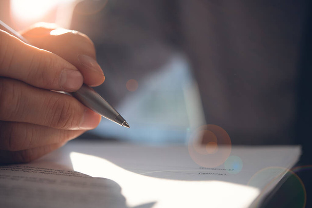 Business agreement, deal concept. Businessman reading rental contract before making a deal. Corporate man with pen in hand working in modern office, signing business document on desk. close up. Flare light effect - Foto, Imagem