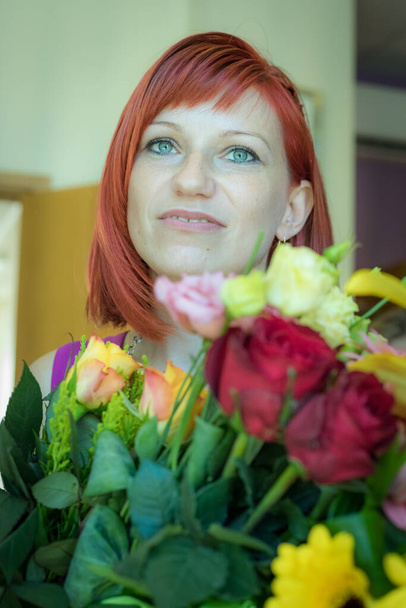 Go Everywhere with flowers woman. A girl with red hair and a great smile - Valokuva, kuva