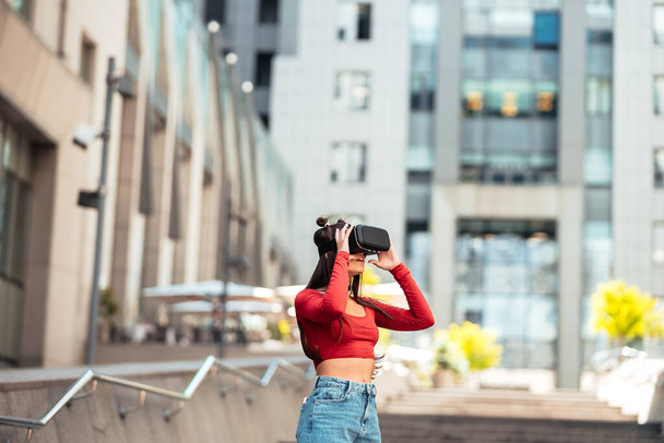 A woman in a virtual reality helmet walks down the street - Fotoğraf, Görsel