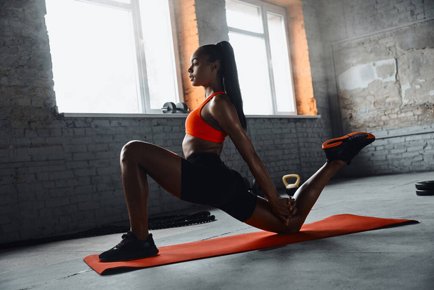 Confident young African woman doing stretching exercises in gym - Photo, Image