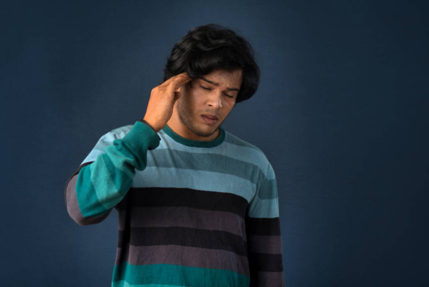 Portrait of young man stress or having the pain of a headache on a grey background. - Foto, imagen