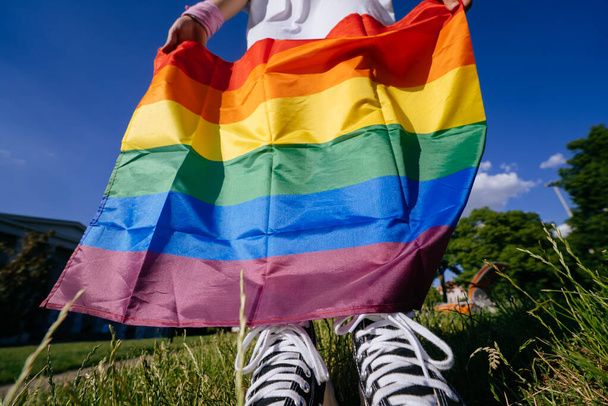 Giovane donna con una bandiera dell'orgoglio LGBT in mano. Vista da vicino, foto ritagliata - Foto, immagini