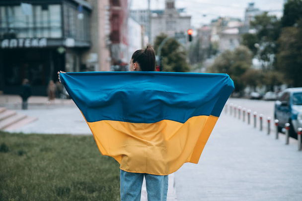 Young woman with national flag of Ukraine walking in the city - Fotoğraf, Görsel