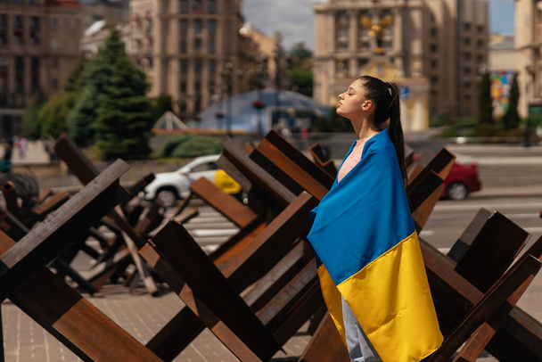 У місті ходить молода жінка з національним прапором України. - Фото, зображення