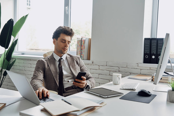 Handsome young man busy working while sitting in office - Photo, Image