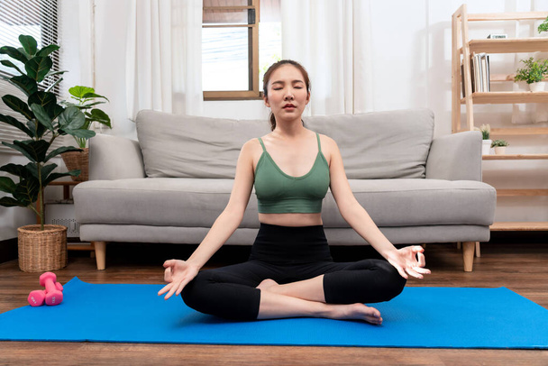 Молода жінка розслабляється на дивані перед тренуванням вправ йоги у своїй вітальні вдома
. - Фото, зображення