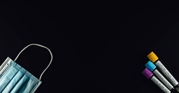 Изолированные пробирки крови Ковид-19 и хирургическая коронная маска для защиты от вируса. Черный фон, медицинская концепция здравоохранения, вид сверху, профилактика пандемии. - Фото, изображение
