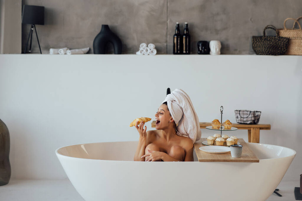 Модная женщина по утрам лежит в ванне и завтракает - Фото, изображение