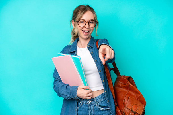 Young student woman isolated on blue background surprised and pointing front - Photo, Image