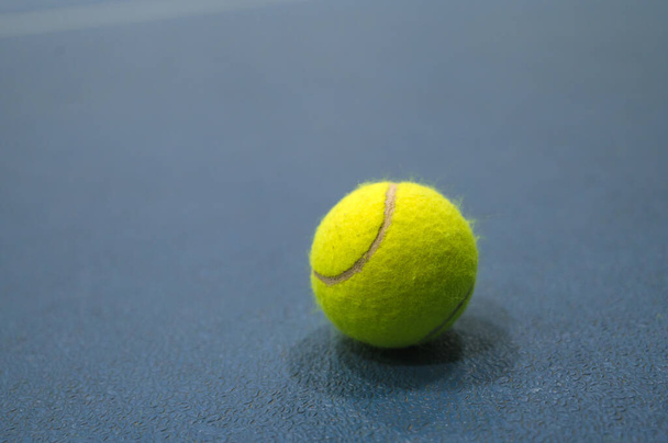 Крупный план теннисного мяча на синей площадке. - Фото, изображение